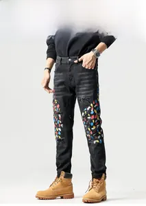Detail van zwarte streetstyle jeans met kleurrijke verfspatten en scheuren