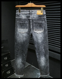 Detail of slim fit snowflake wash denim jeans with ethnic trim on back pocket
