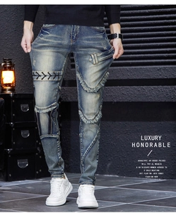 Detail of distressed men's slim jeans featuring vintage wash with patchwork and lace-up design