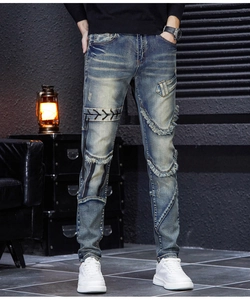 Detail view of men's slim fit distressed blue jeans with patchwork and lace-up design