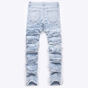 Men's light blue distressed jeans with heavy fringe stack and frayed hem detail