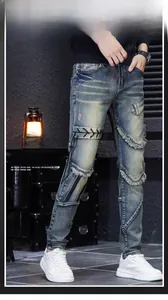 Detailed close-up of distressed denim jeans with patchwork and cross strap details