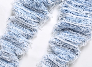 Macro view of light blue denim with heavy distressed fringe and frayed texture details