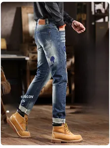 Detail of distressed blue jeans with cross embroidery patches and vintage rip accents