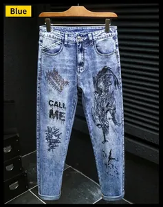 Detail of blue men's jeans with black dragon embroidery and CALL ME print on fabric