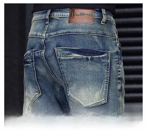 Detail of blue denim jeans featuring back pocket with distress and leather brand patch