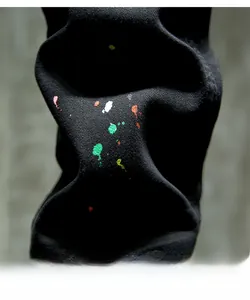 Detail view of black slim jeans featuring colorful paint splatter and twill fabric texture