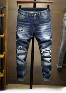 Détails d'un jean bleu coupe ajustée avec déchirures et éclaboussures de peinture colorées