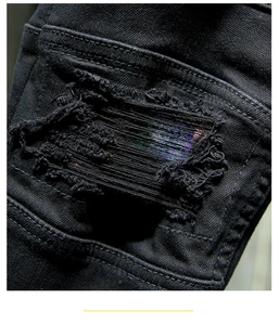 Detailed close-up of distressed denim jeans with colorful fabric underlay and ripped effects