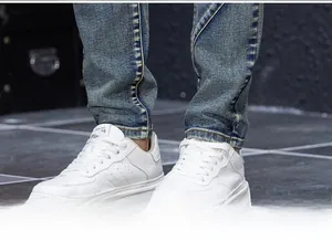 Detail shot of slim-fit distressed blue jeans paired with white casual sneakers