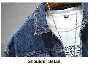 Détail de l'épaule d'une veste en jean bleue avec coutures orange et chaîne argentée