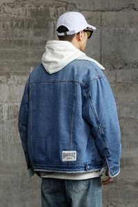 Detail of blue denim jacket with thick white sherpa lining and rear brand patch