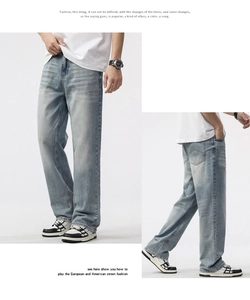Detailed close-up showing light blue washed denim jeans with vintage whiskers and loose fit