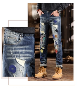 Detail of distressed slim fit jeans with colorful embroidery patches and ripped design