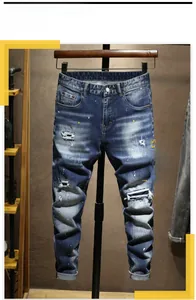 Vue détaillée du jean en denim bleu vintage délavé avec trous usés et taches de peinture