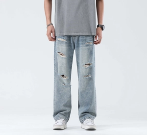 Detailed view of light blue washed denim jeans featuring heavy distressed and ripped design