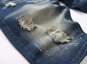 Detailed macro shot of vintage distressed denim shorts featuring heavy ripped hole textures