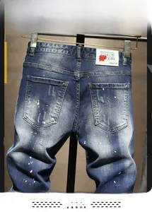 Détail de jean bleu délavé vintage avec taches de peinture et écusson blanc à l'arrière