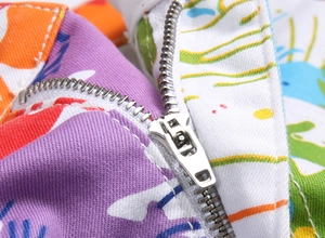 Détail macro du zip en métal argenté sur short en jean stretch avec imprimé numérique