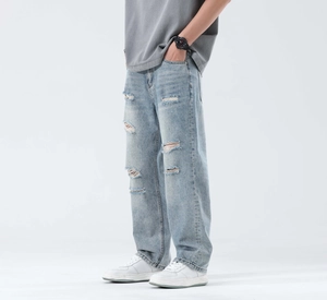 Detail of light blue distressed jeans with frayed rips and faded whisker texture