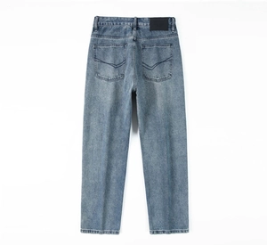 Detail view of washed light blue denim jeans with leather patch and arch back pocket stitching