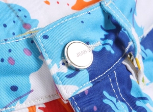 Détail du bouton argenté JEANS et de l'imprimé numérique coloré sur le short en jean blanc