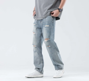 Close-up of light blue washed denim jeans with distressed holes and whiskering details