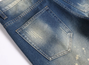 Detail of vintage washed blue denim shorts featuring orange stitching and worn pockets