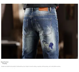Detail of blue jeans featuring washed finish, cross patchwork, and leather label on back pocket