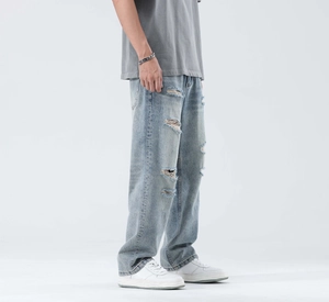 Detail of light blue ripped jeans showing street style distressed cuts on wide legs