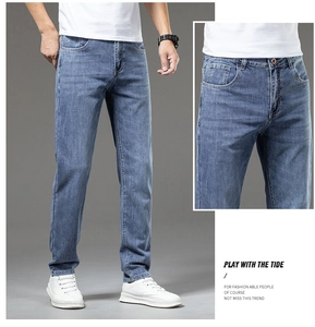 Detail view of mens light blue slim fit denim jeans showing washed texture and five pockets