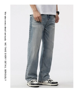 Detail of light blue washed denim fabric with vintage whiskers on loose straight jeans