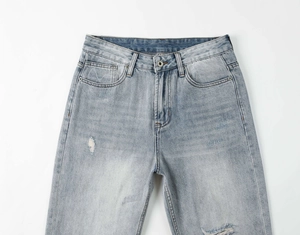 Dettaglio dei jeans blu lavati con bottone in metallo e dettagli in stile vintage