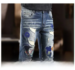 Detail of slim-fit distressed denim jeans featuring unique cross and dot patchwork patches
