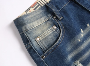 Detailed macro view of distressed denim fabric with silver rivets and vintage wash effect