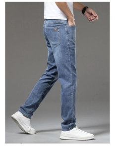 Detail of vintage blue denim texture and orange logo patch on men's slim fit jeans