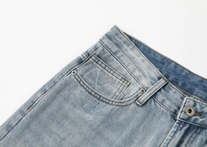 Dettaglio della vita dei jeans lavaggio blu chiaro con bottone in metallo e cuciture
