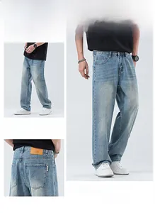 Détail de ce jean bleu clair délavé avec patch en cuir marron et coupe large tendance