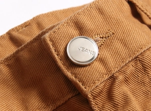 Vue macro du bouton argenté de jean avec texte gravé sur tissu sergé de coton kaki