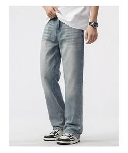 Detail of light blue straight-leg jeans with natural fading and vintage wash textures