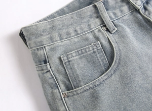 Detail of light blue denim fabric texture and silver metal rivets on casual cargo shorts