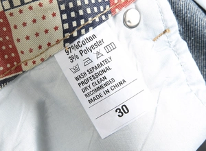 Detailed macro view of denim shorts care label showing 97% cotton fabric and size 30