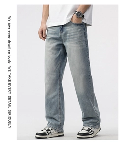 Side view of men's loose straight-leg light blue washed denim jeans with whisker details