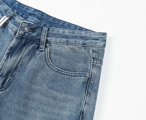 Detail view of denim jeans waist with metal button and light blue washed fabric texture