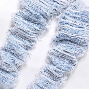 Men's loose light blue distressed denim jeans with heavy fringe and ripped detailing