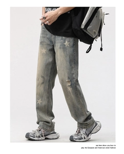 Détail du jean denim délavé bleu avec imprimé étoile et détails de genoux déchirés usés