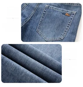 Detail view of denim jeans featuring a classic back pocket with orange double stitching