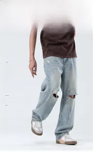 Vue détaillée d'un jean ample pour homme avec genoux déchirés et délavage bleu clair