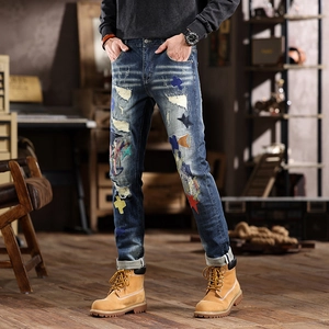 Distressed slim-fit denim jeans with patchwork embroidery and vintage streetwear aesthetic