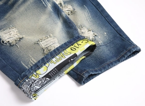 Detailed close-up of distressed denim shorts with ripped holes and printed cuffs